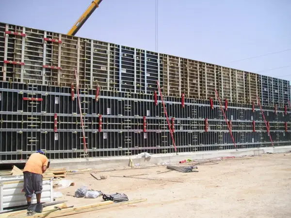 Un ouvrier travaille sur un grand petit coffrage béton, prêt pour le coulage. La structure métallique est impressionnante.